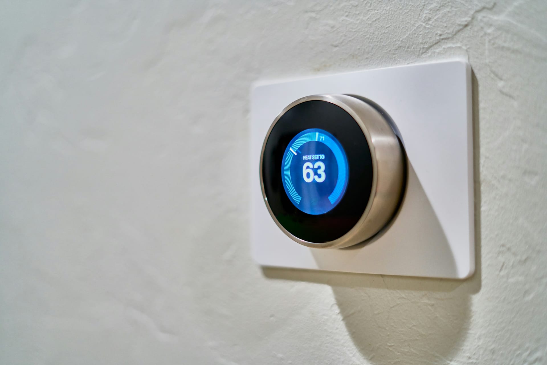 A wall-mounted smart thermostat with an illuminated display
